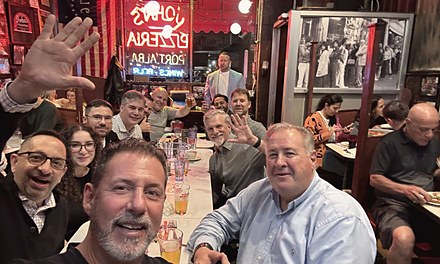Rob Lancit at a long table of friends at John's Pizzeria