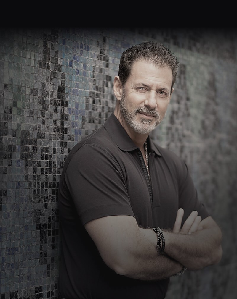 Rob Lancit, arms crossed, standing against a dark tiled wall