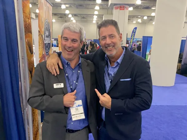 Rob Lancit and a man in a gray blazer on a trade show floor