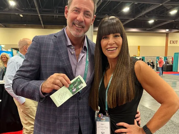 Rob Lancit and a woman with a conference badge on a red carpet at an expo