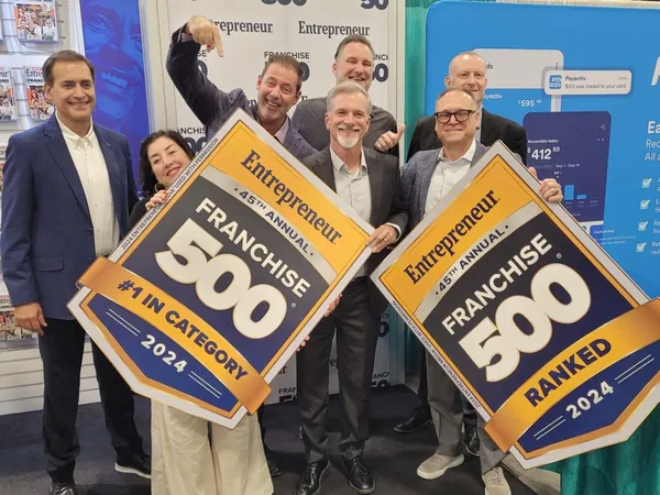 A group holding two Entrepreneur Franchise 500 2024 signs, #1 in Category and Ranked