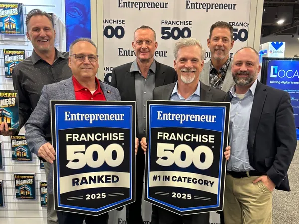 A group holding two Entrepreneur Franchise 500 2025 signs, Ranked and #1 in Category
