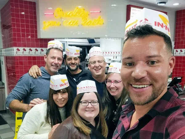 Rob Lancit and friends wearing paper hats in a selfie at a burger restaurant