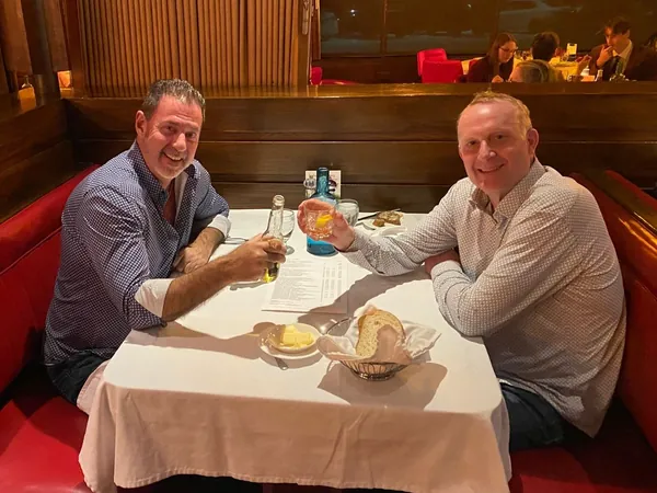 Rob Lancit and a man raising glasses at a restaurant booth