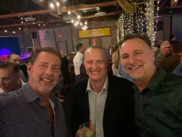 Rob Lancit, Stewart and Mike Millett smiling together at an evening event
