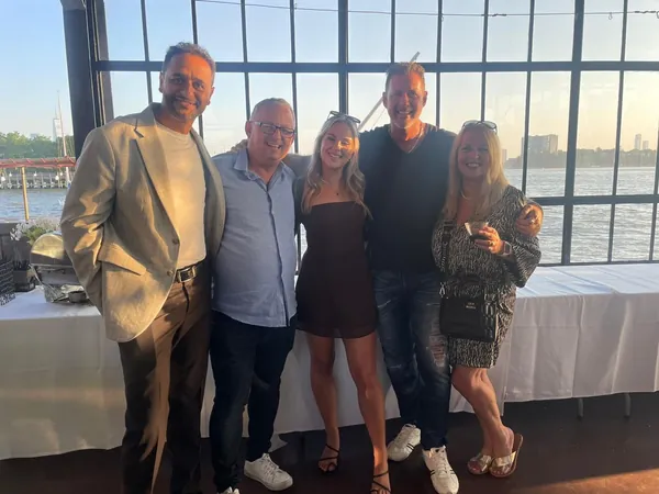 Rob Lancit with four friends in front of windows over the water